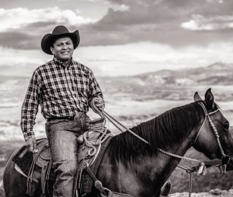 Santa Fe jeweler and photographer Arland Ben sits on a horse smiling at the camera