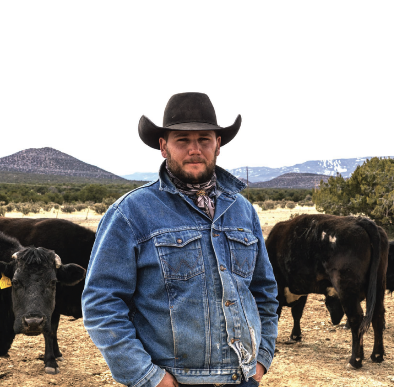 Santa Fe's American Cowboy Rio Dewitt looks into the camera, his cows are in the background