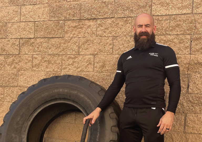 Jeremy Jamieson stands next to a large tire